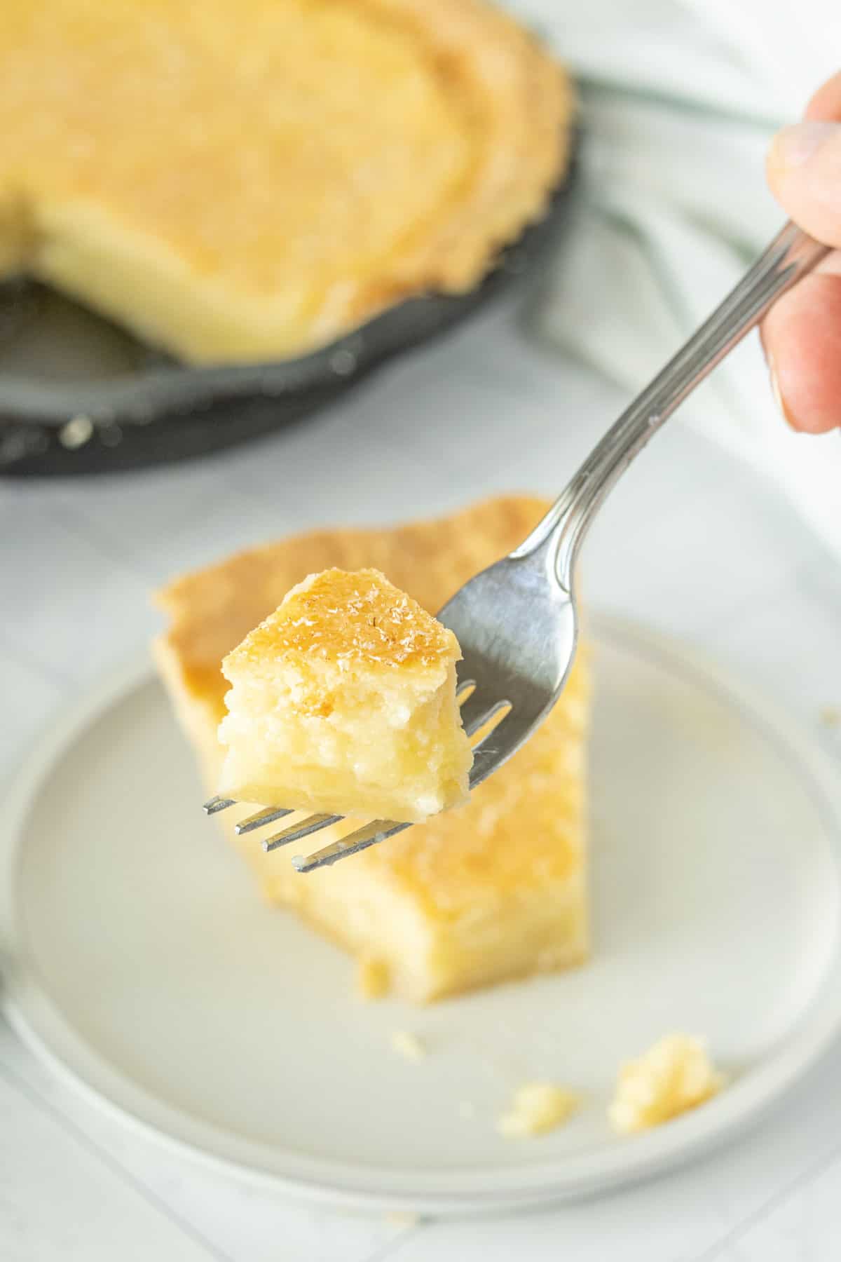 A person holding a piece of pie with a fork.