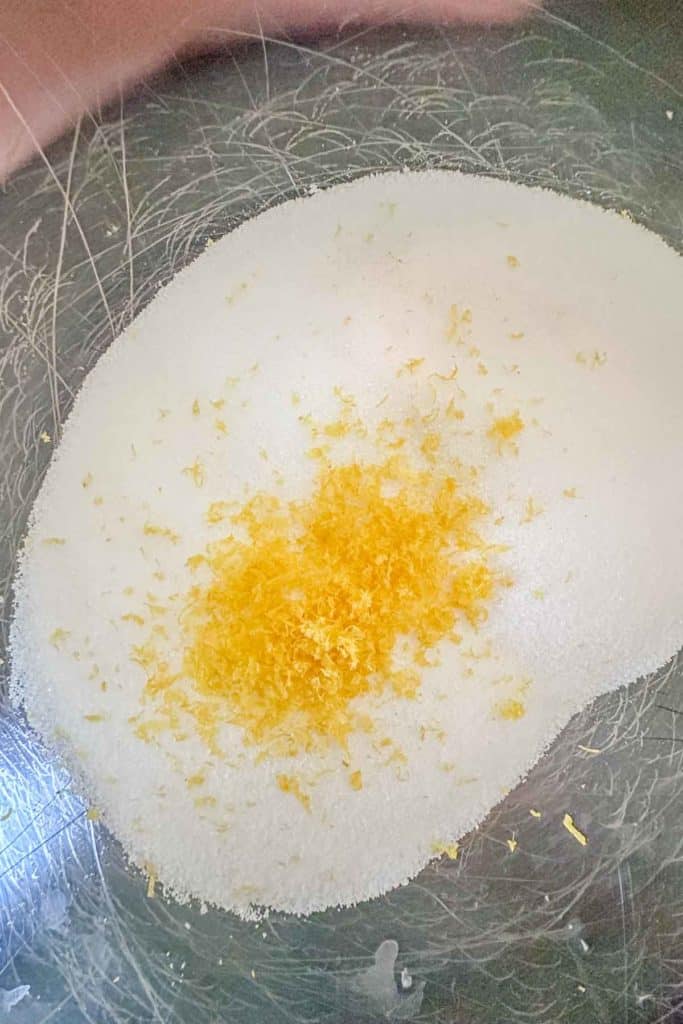 Sugar and lemon zest in a metal bowl.