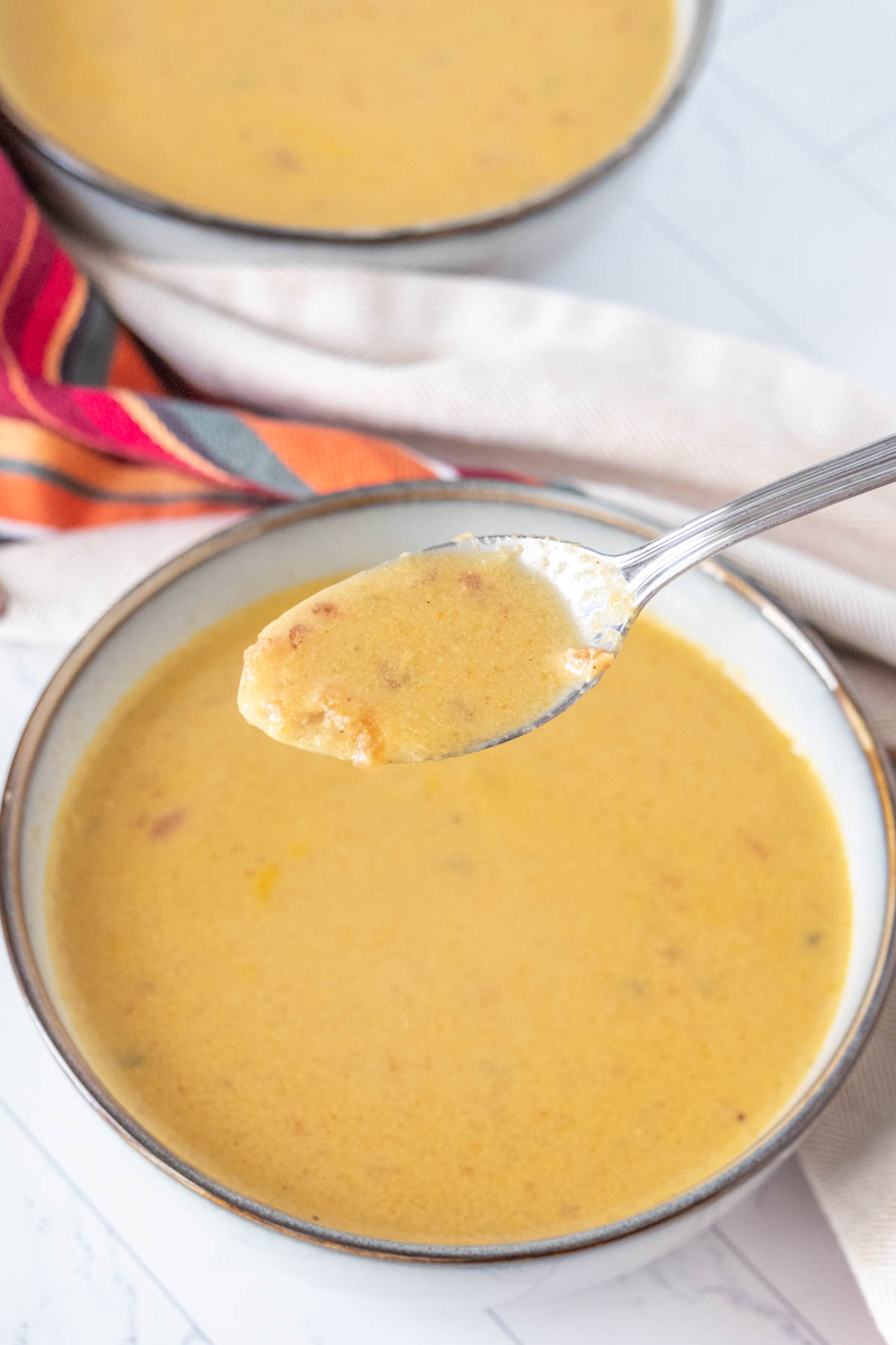 Spoonful of corn soup held up over bowl.