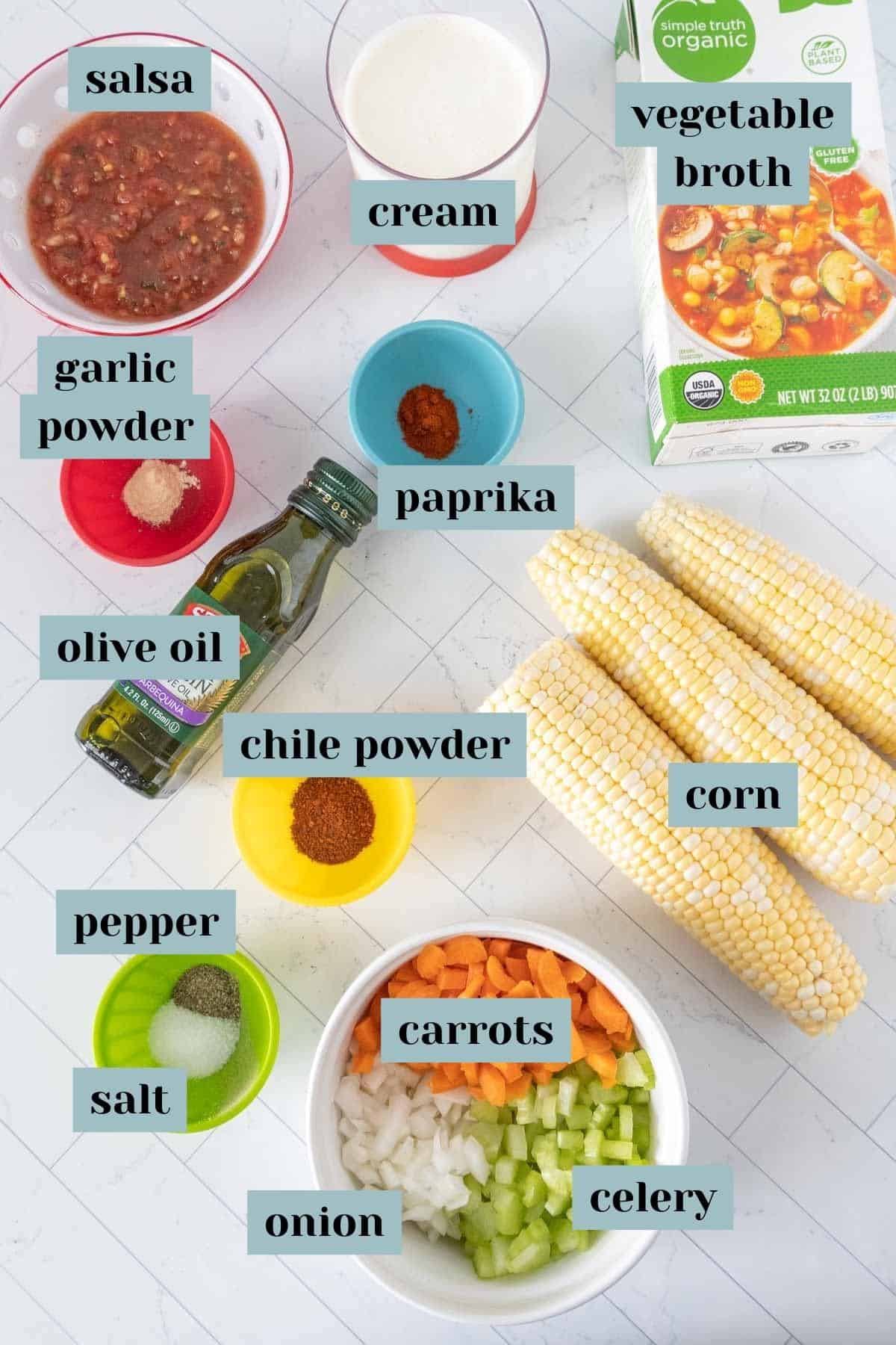 Ingredients for corn soup on a tile surface with labels.