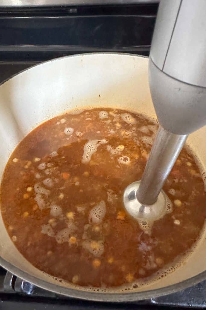 Blending corn soup with an immersion blender in the pot.