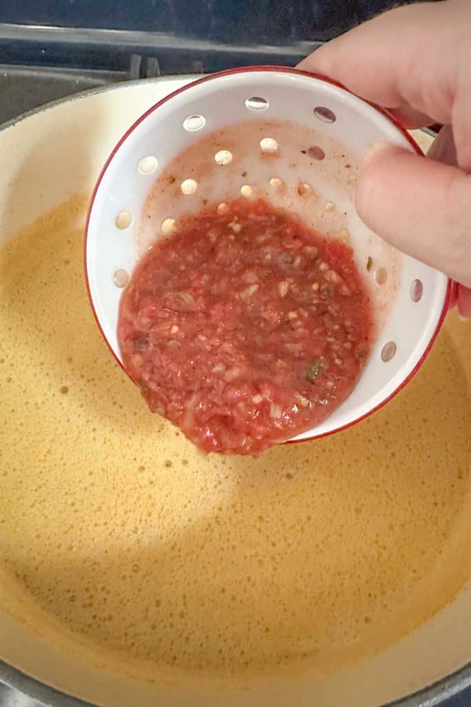 Adding salsa to corn soup.