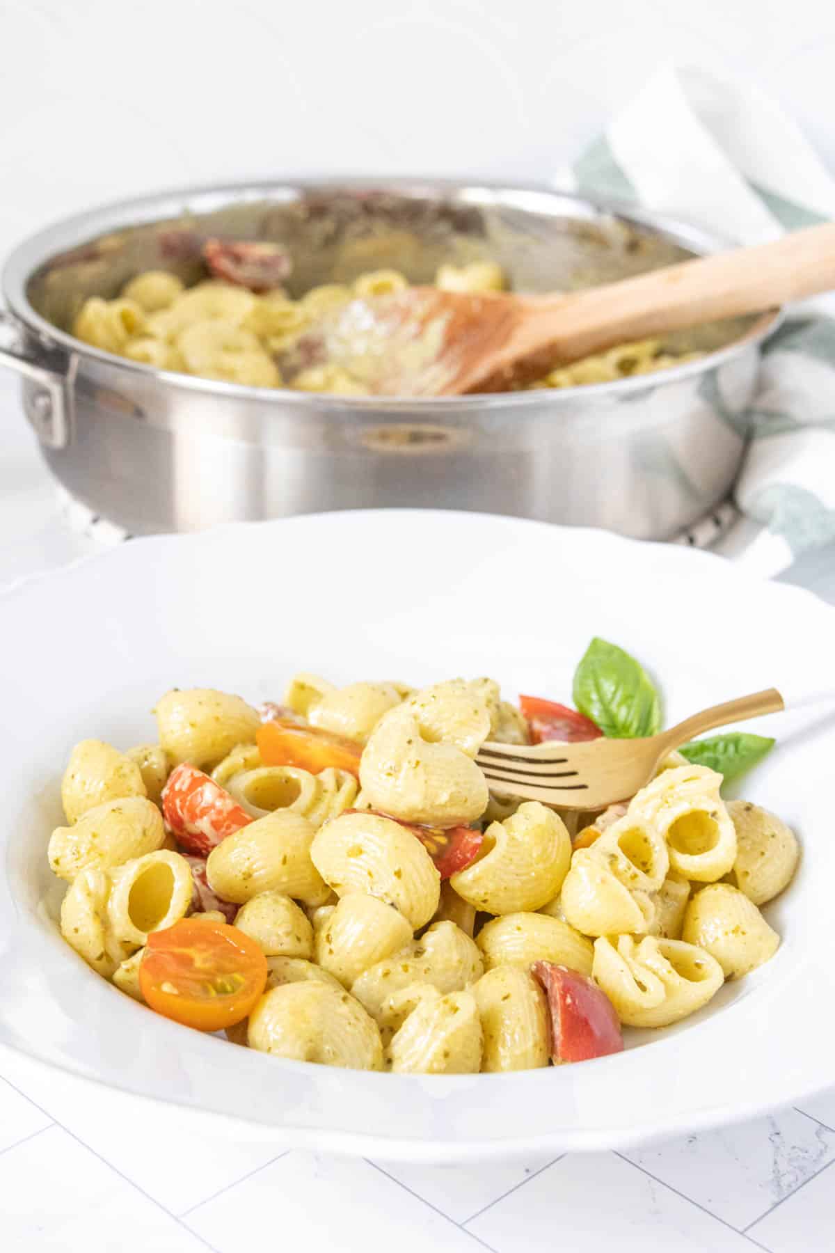 Creamy pesto pasta in a low bowl with the pot behind.