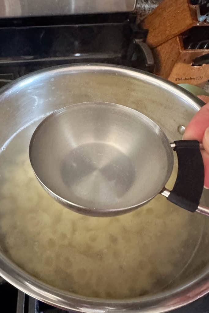 Holding up a scoop of pasta water to use for sauce.