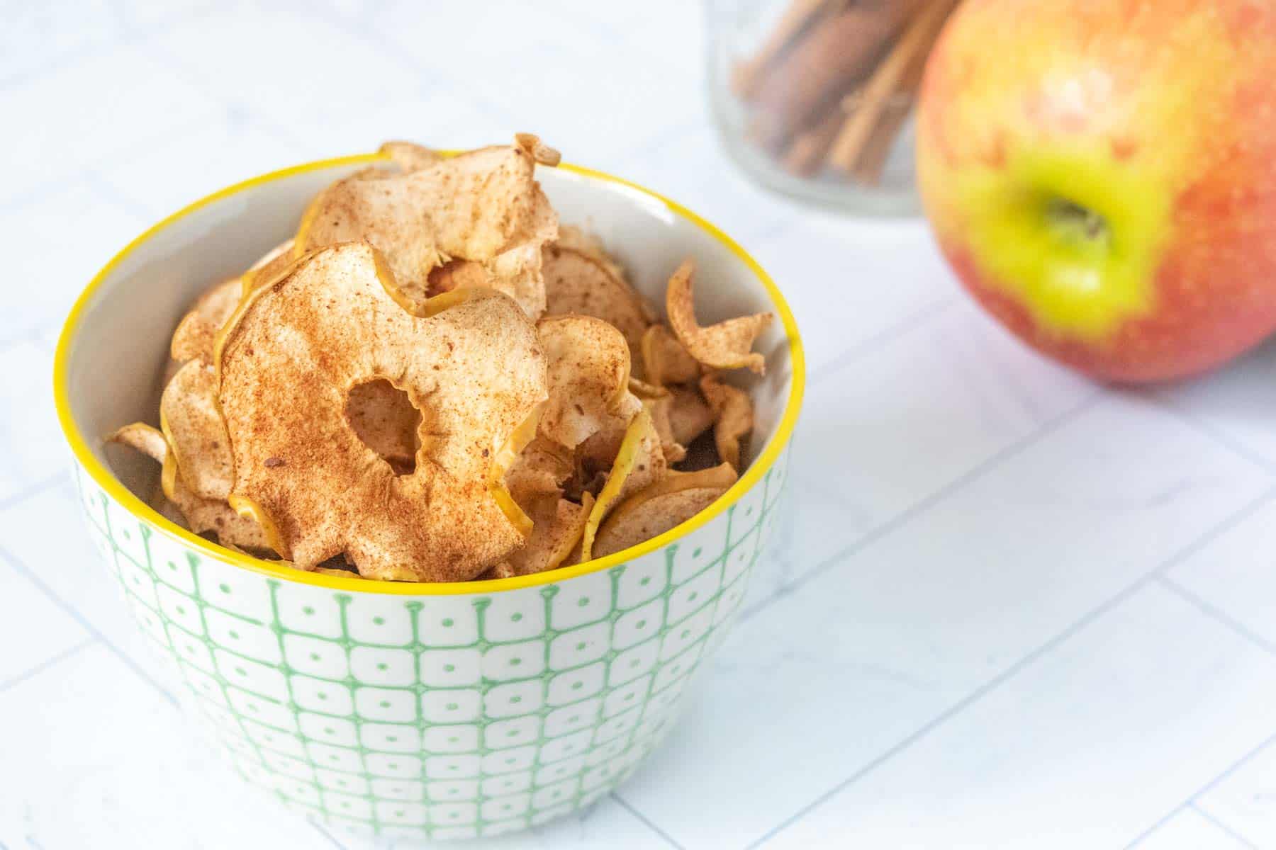 Apple chips in a cup with cinnamon sticks.