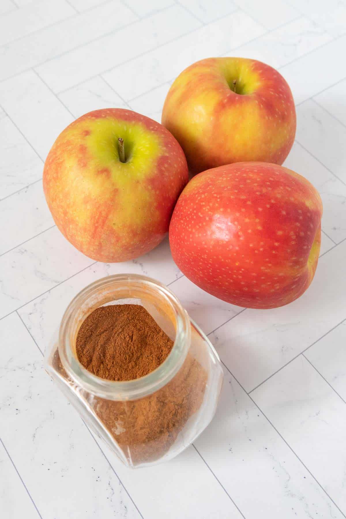 Apples and cinnamon on a white table.