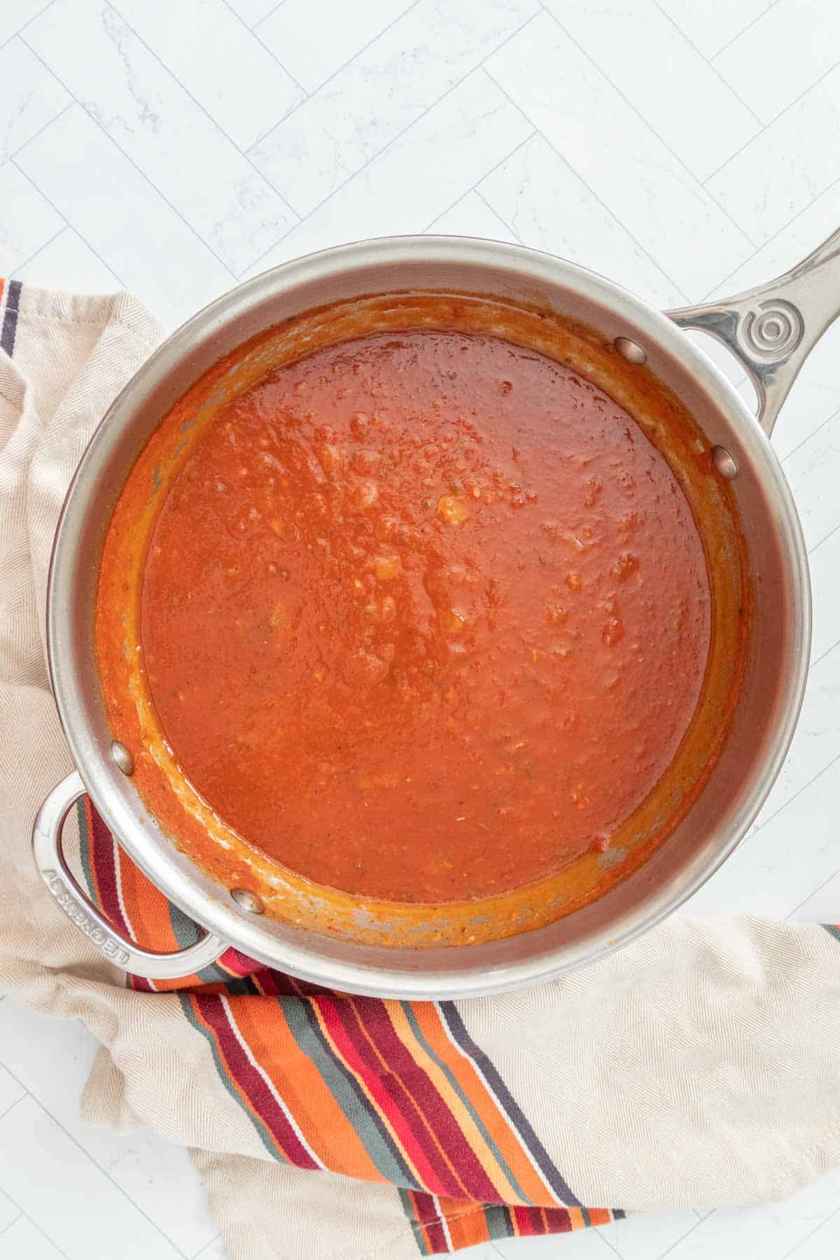 A pan full of tomato sauce on a table.