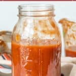 A glass mason jar filled with easy spaghetti sauce sits on a counter, its vibrant red contents visible alongside splatters on the rim and background. Text above reads "easy spaghetti sauce.