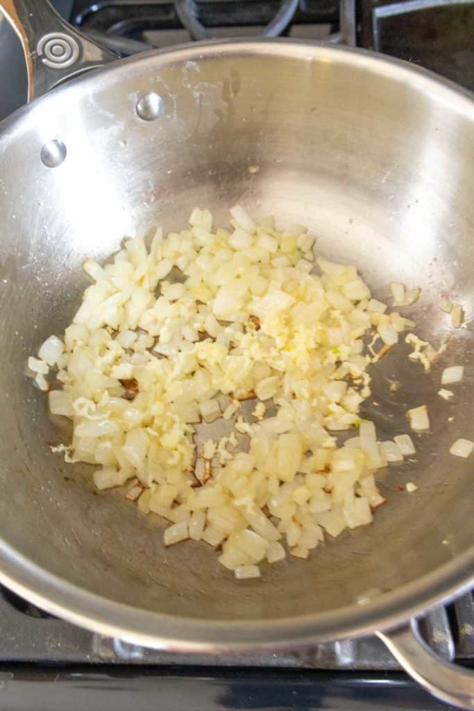 Sauteing onions in a pan on a stove.