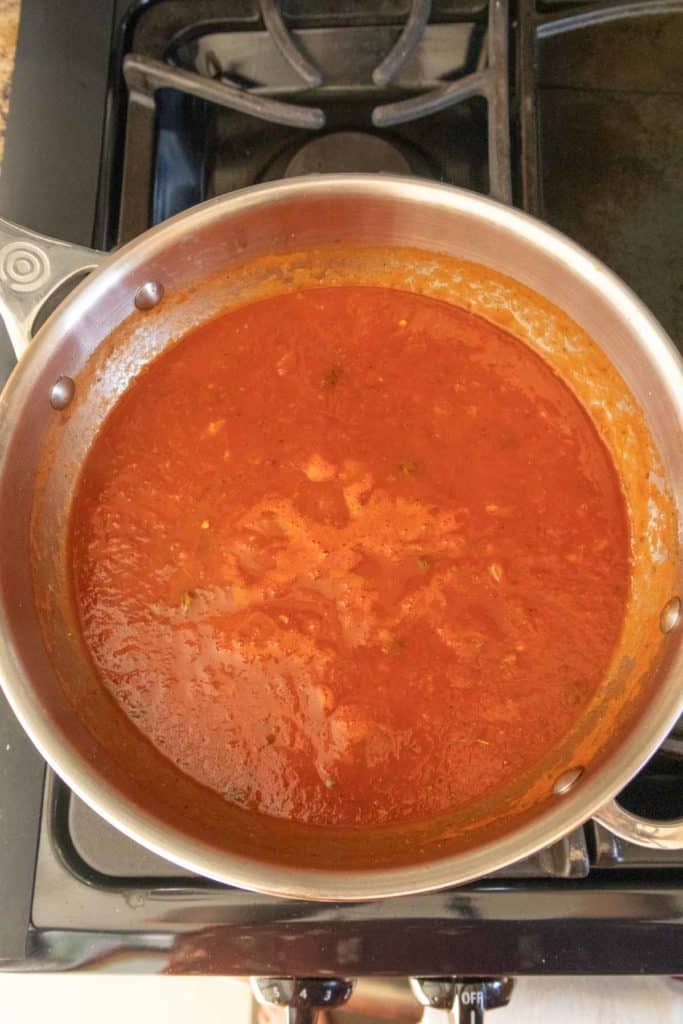 A pot of tomato sauce on a stove top.