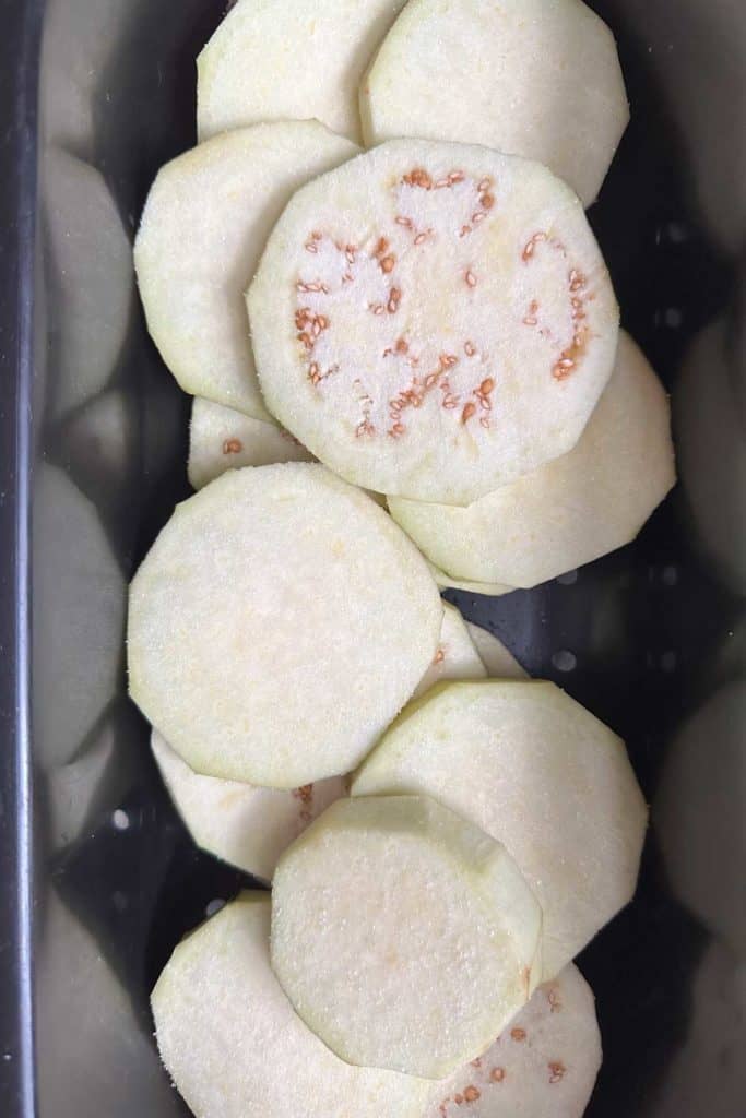 Salted eggplant slices in a colander.