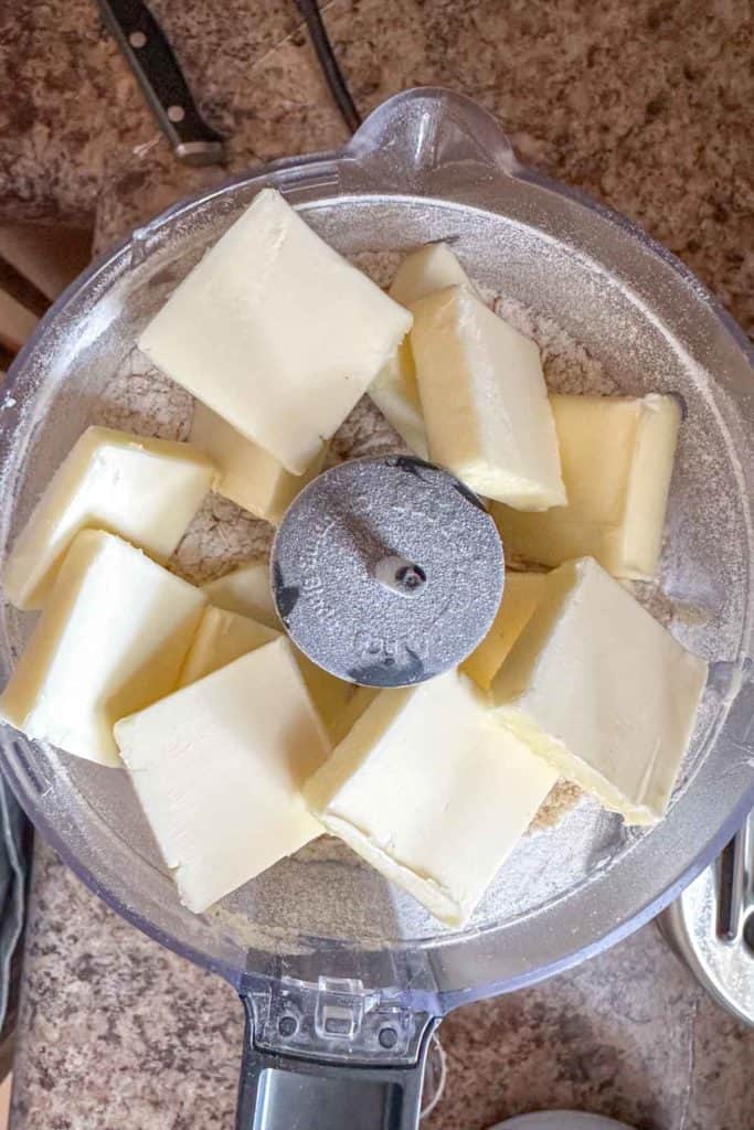 Butter in a food processor on a counter.