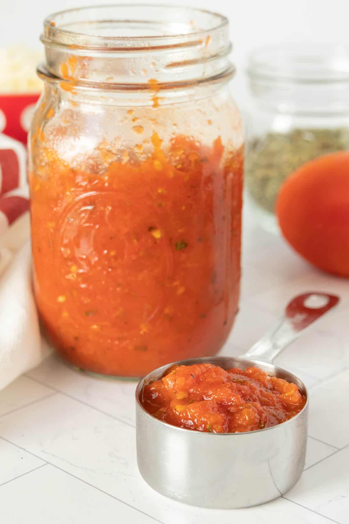 A jar of pizza sauce with a spoon next to it.