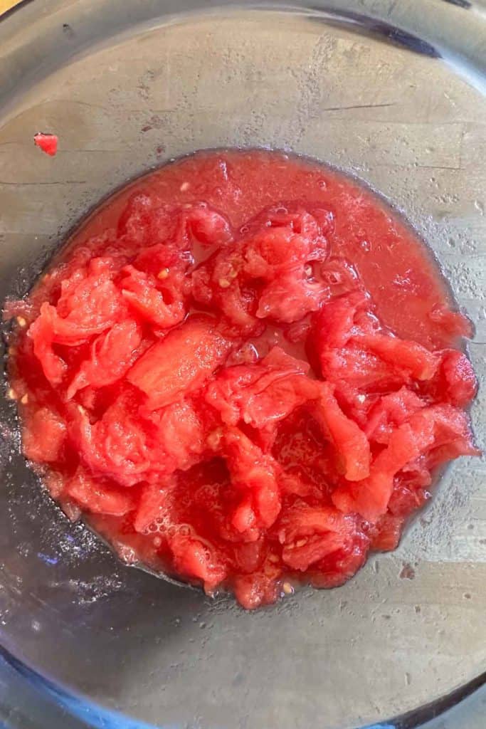 A bowl of crushed tomatoes on a wooden table.