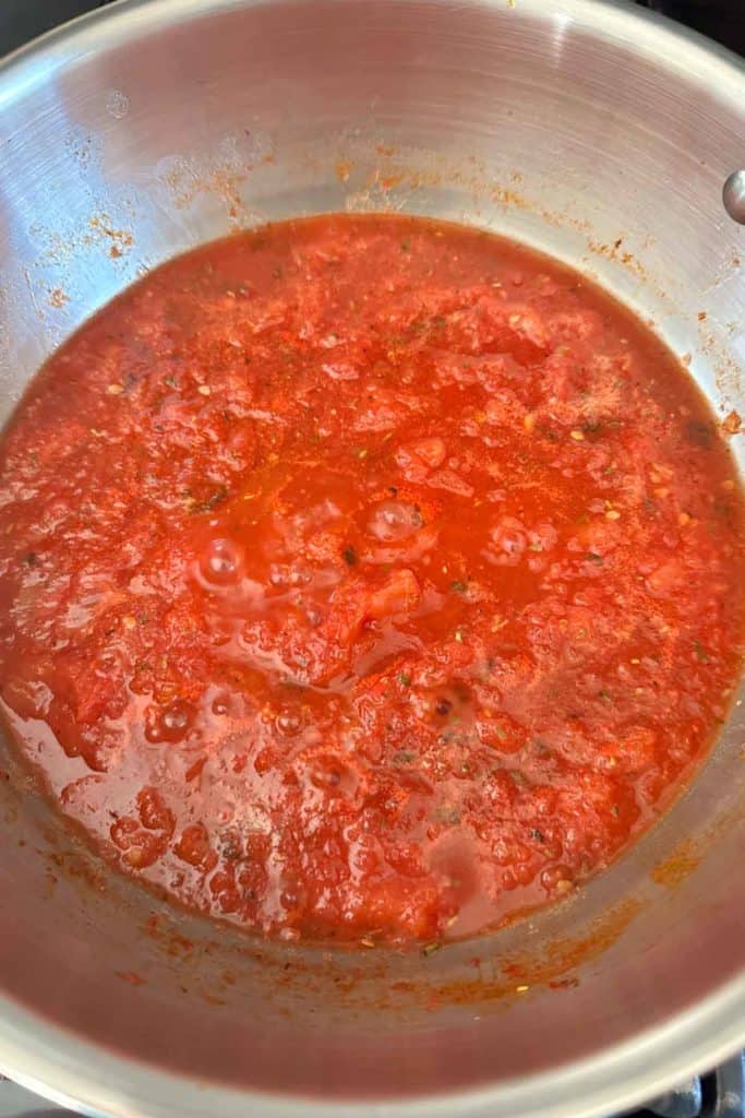 A pot of pizza sauce on a stove top.