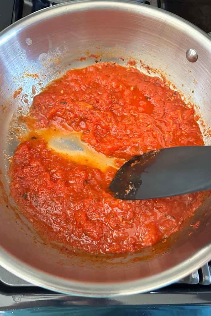 A pan of pizza sauce with a spatula in it.