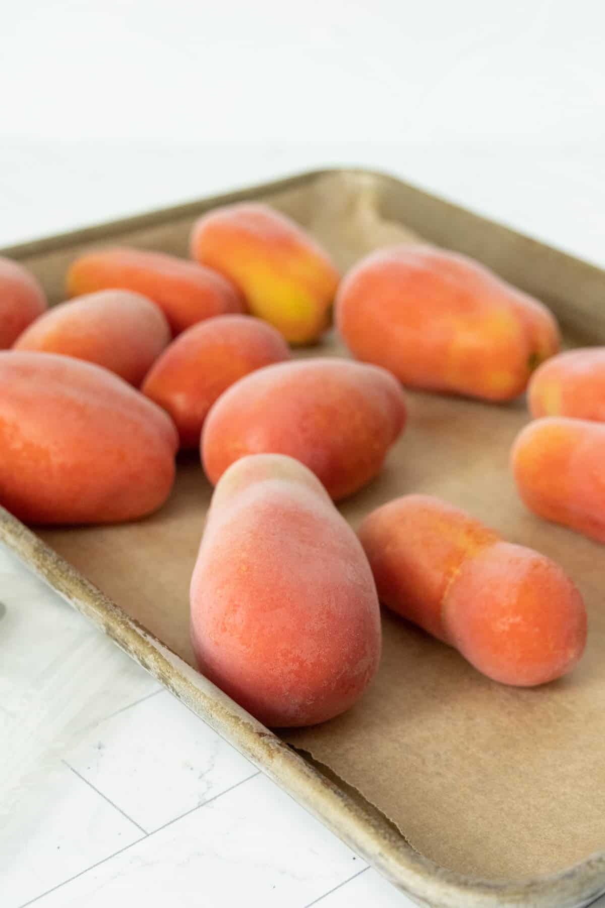 Frozen tomatoes on a baking sheet.