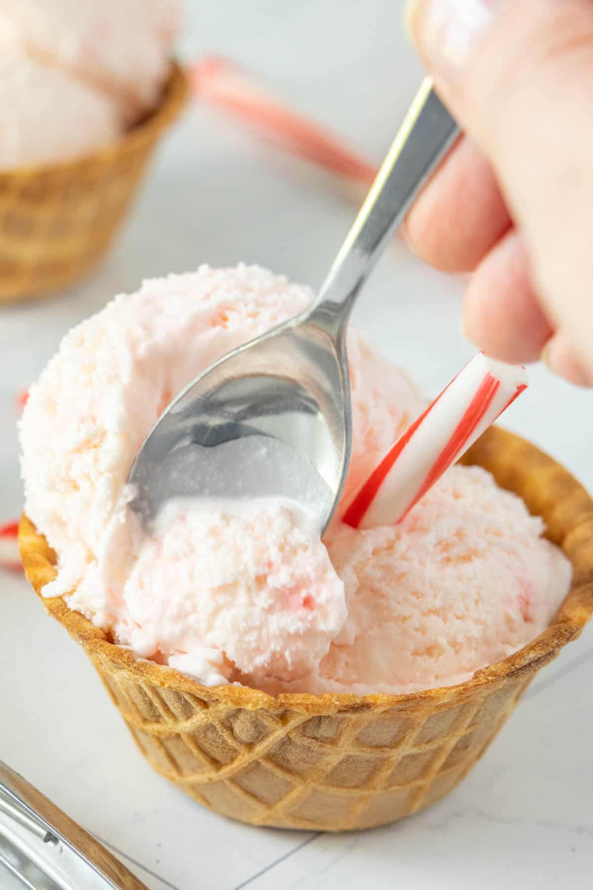 Candy cane ice cream in a bowl with a spoon.