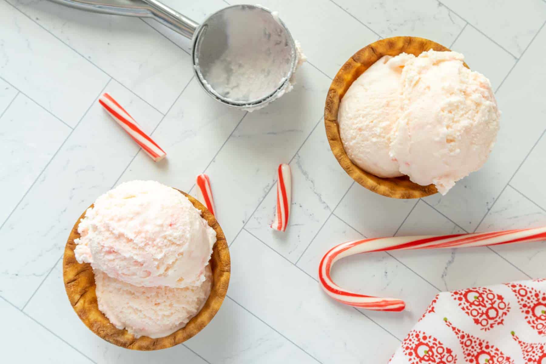 Two bowls of ice cream with candy canes and spoons.