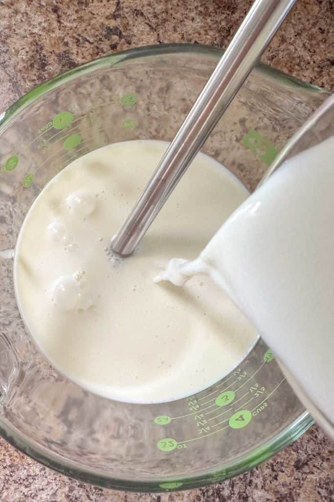 Milk being poured into a glass bowl.