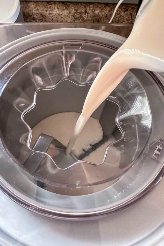 A bowl of ice cream mix being poured into a mixer.