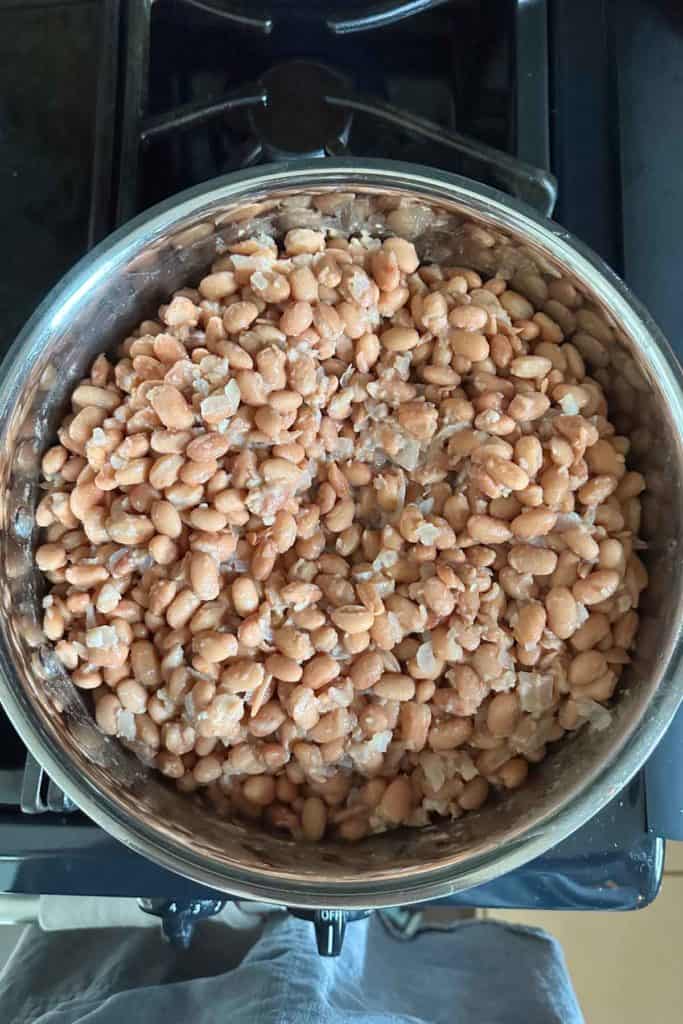 A pan full of beans sitting on top of a stove.