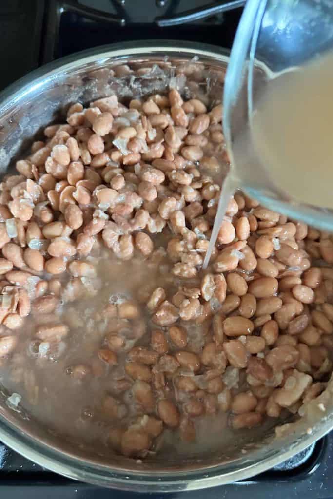 Liquid being poured into a pan with beans.