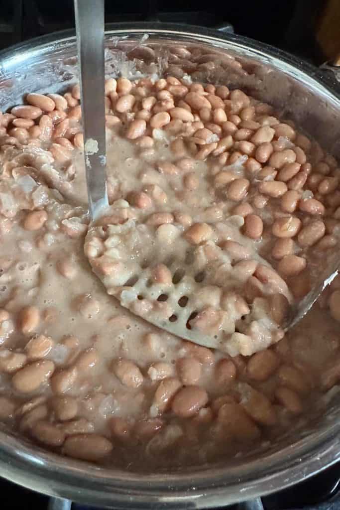 Mashing refried beans on a stove.