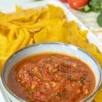 A bowl of mexican salsa with tortilla chips.