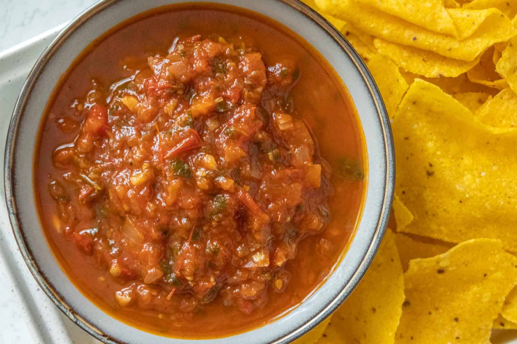A bowl of mexican salsa with tortilla chips.