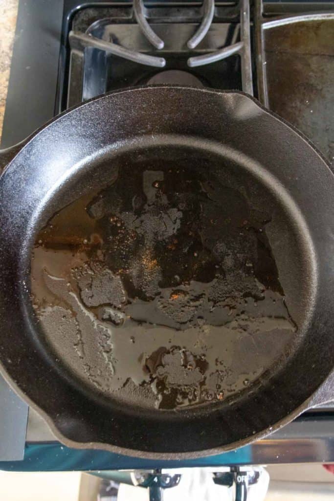 A skillet heating with olive oil on a stove.