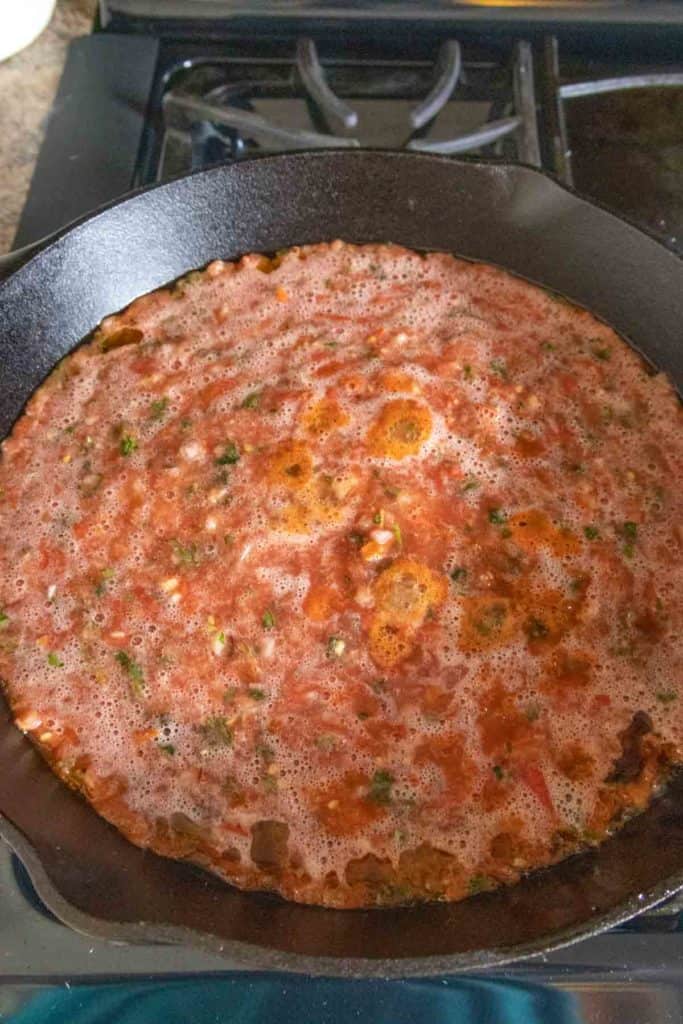 A skillet with a salsa in it on top of a stove.