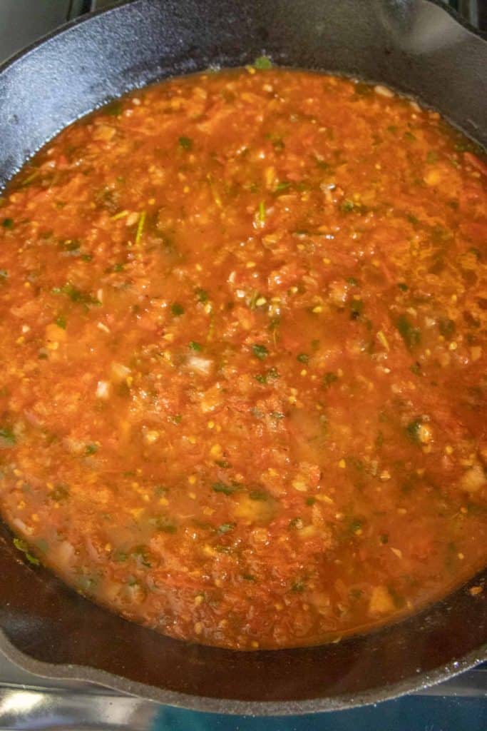 A skillet filled with salsa on a stove.