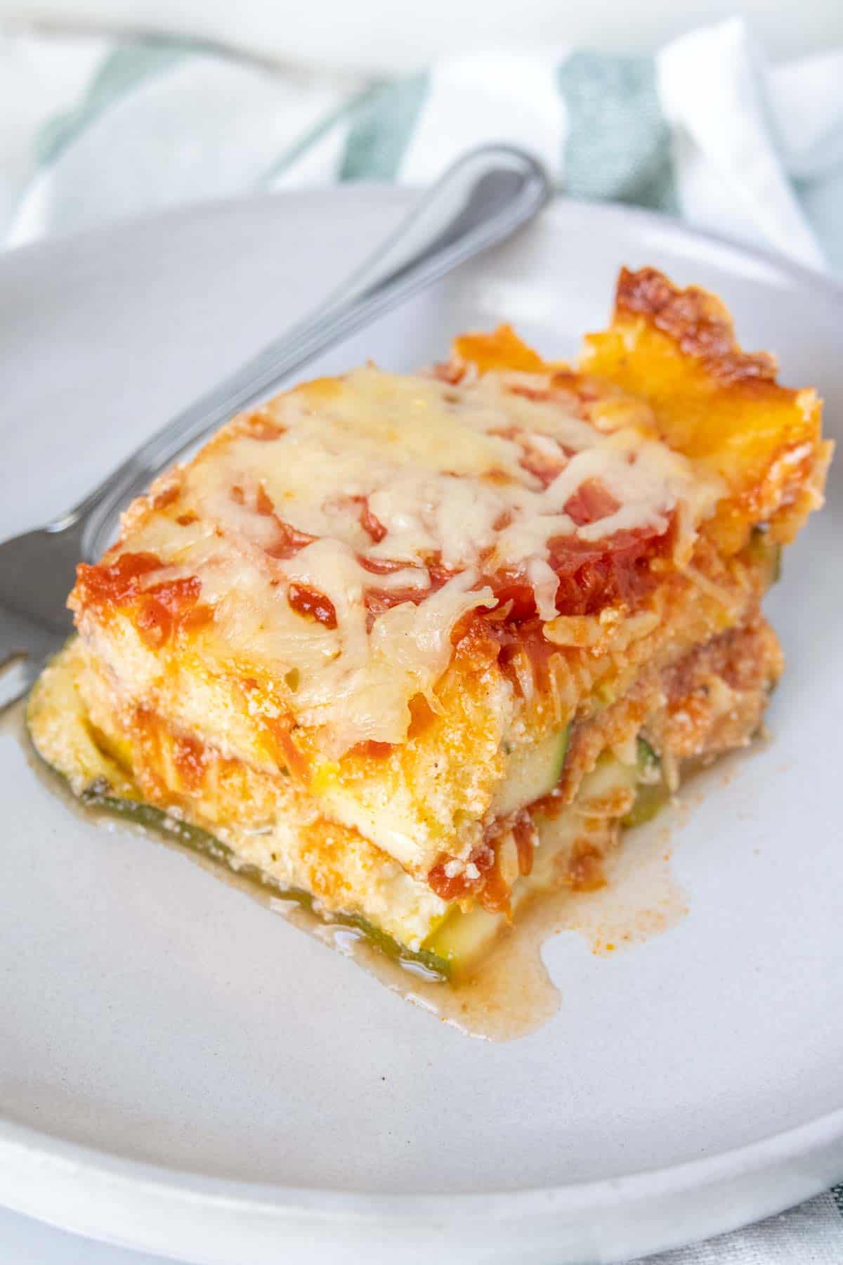 Gray plate with a slice of zucchini lasagna and a fork.