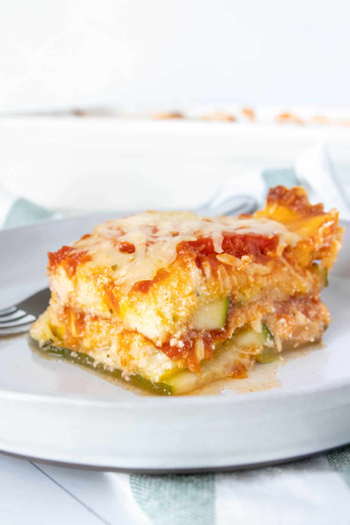 Slice of zucchini lasagna on a gray plate from the side.