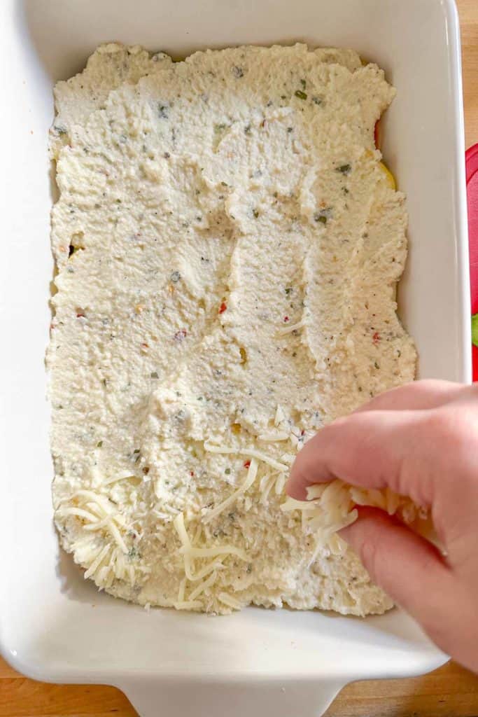 Sprinkling mozzarella on top of ricotta layer for zucchini lasagna.