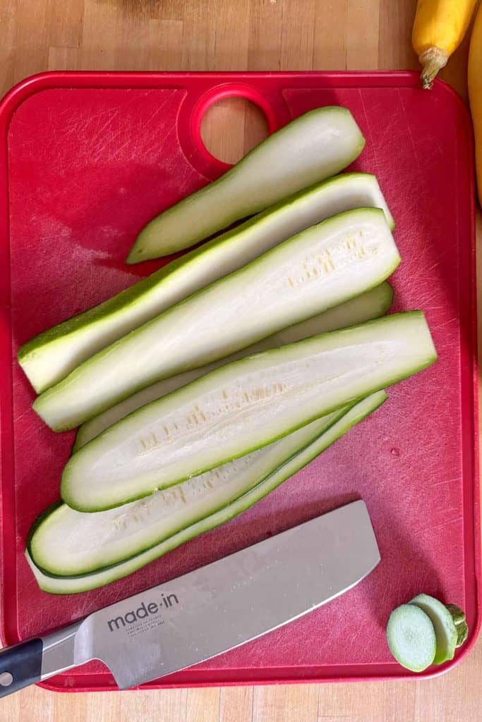 Sliced zucchini on a cutting board with a knife.
