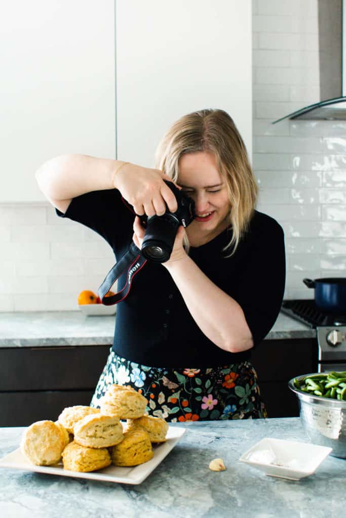 White woman taking photos of biscuits.