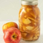 A mason jar with apples next to it.