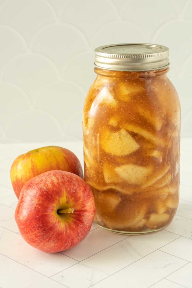 A mason jar with apples next to it.