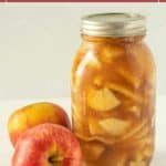 A jar of homemade apple pie filling sits beside two fresh apples, with the text "apple pie filling for canning" displayed above.