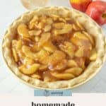A bowl filled with rich apple pie filling sits in a flaky pie crust, accompanied by two apples and a jar in the background. Text at the bottom reads, "homemade apple pie filling.