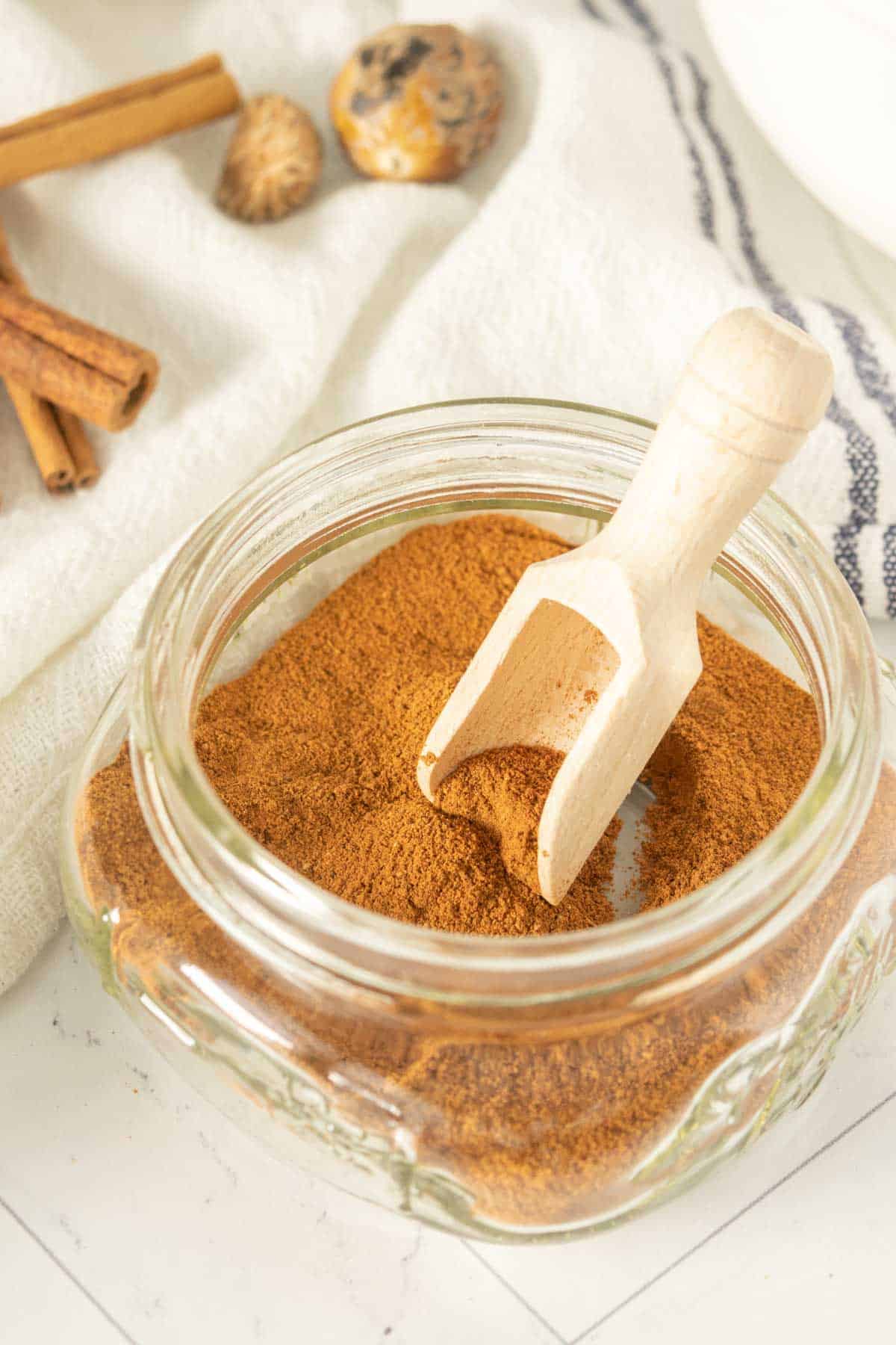 Apple pie spice in a glass bowl with cinnamon sticks.