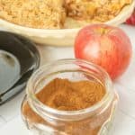 A bowl of apple pie spice next to a pie and a bowl of apples.