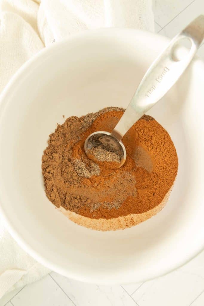 Cinnamon powder in a white bowl with a spoon.