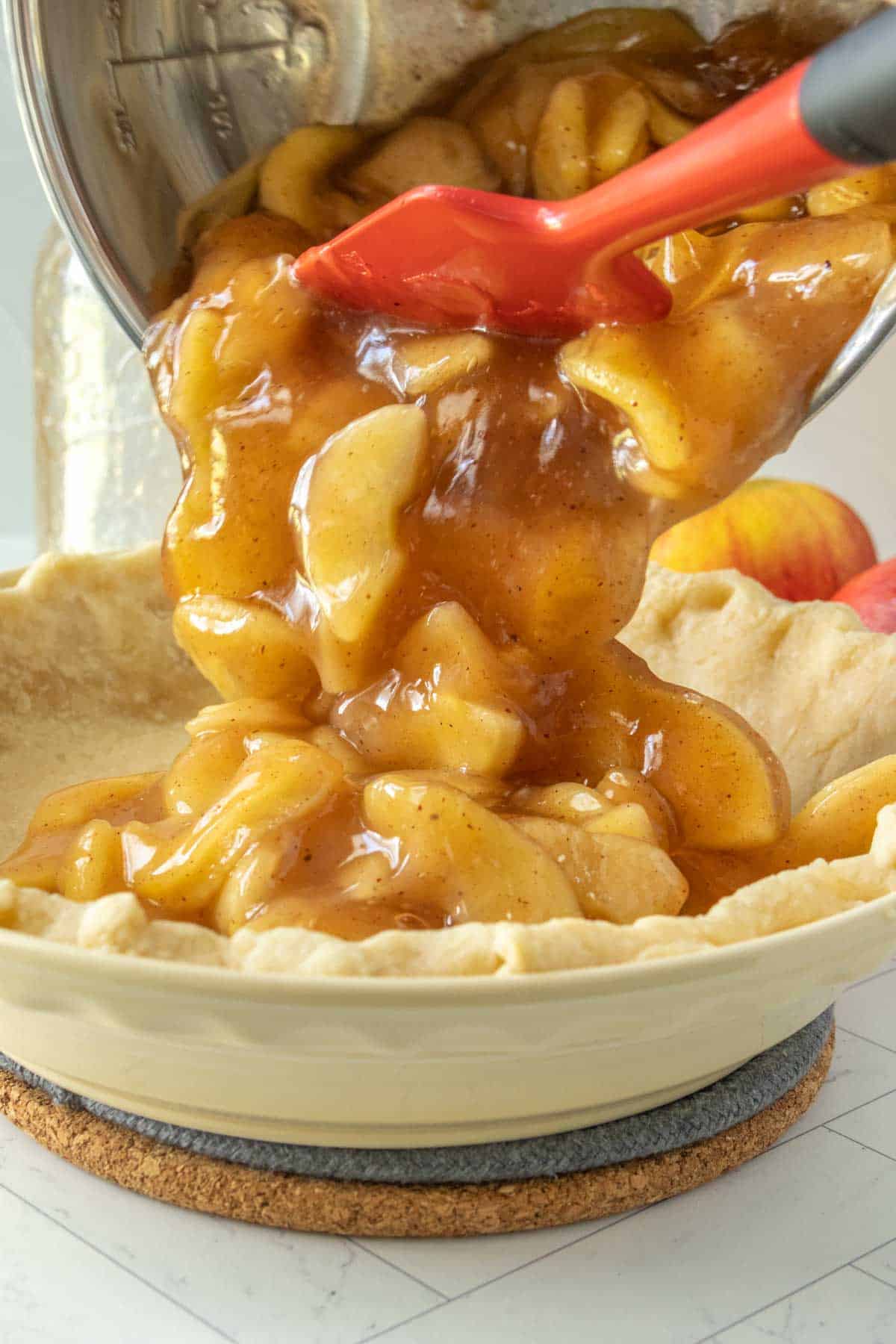 Apple pie filling being poured into a crust.