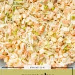 A bowl of apple slaw features crunchy shredded cabbage, carrots, crisp apple pieces, sliced almonds, and green onions.