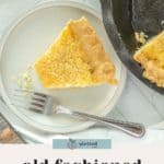 A slice of buttermilk pie on a plate with a fork sits beside a cast iron skillet filled with more rich, homemade buttermilk pie.