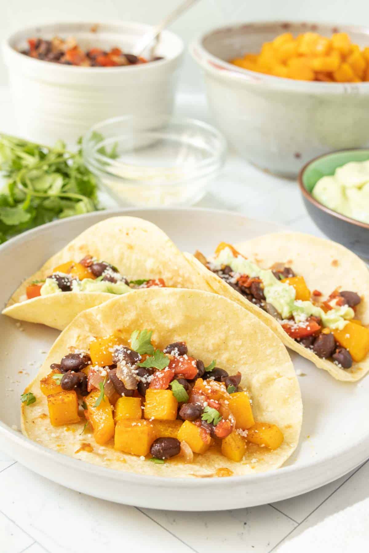 Three black bean squash tacos on a white plate.