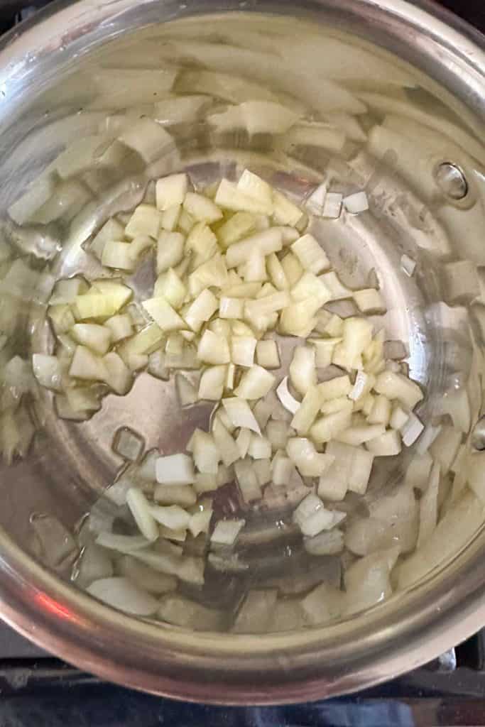 Onions being sautéed in a pan on a stove.